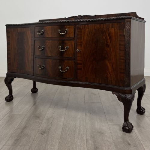 fig 3. An Edwardian mahogany sideboard featuring three central drawers flanked by two cupboard doors, resting on cabriole legs with claw and ball feet.