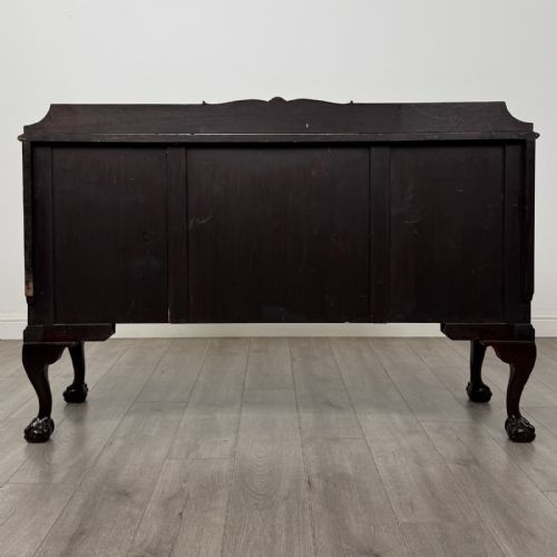 fig 6. An Edwardian mahogany sideboard featuring three central drawers flanked by two cupboard doors, resting on cabriole legs with claw and ball feet.
