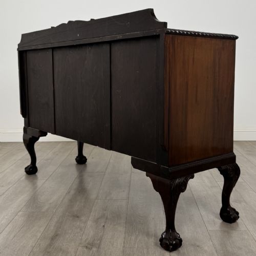 fig 7. An Edwardian mahogany sideboard featuring three central drawers flanked by two cupboard doors, resting on cabriole legs with claw and ball feet.