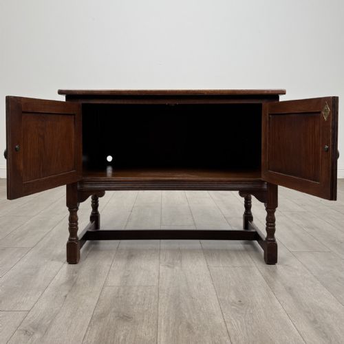 fig 1. A dark oak cupboard featuring two linenfold carved door panels, decorative metal hinges, ring pull handles, turned legs, and a lift top.