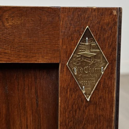 fig 2. A dark oak cupboard featuring two linenfold carved door panels, decorative metal hinges, ring pull handles, turned legs, and a lift top.