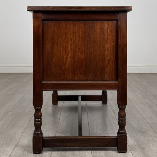 fig 4. A dark oak cupboard featuring two linenfold carved door panels, decorative metal hinges, ring pull handles, turned legs, and a lift top.