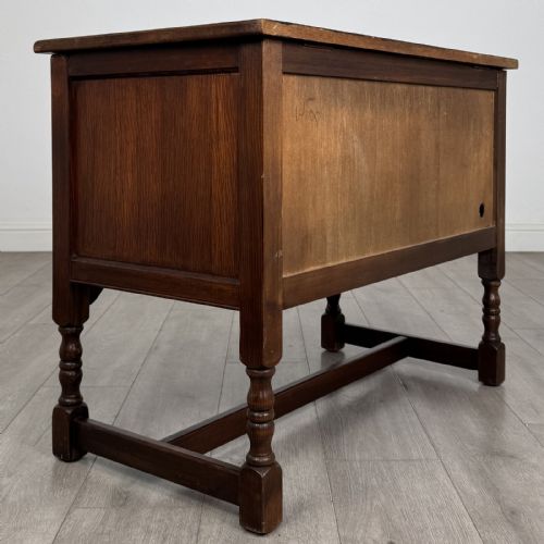 fig 5. A dark oak cupboard featuring two linenfold carved door panels, decorative metal hinges, ring pull handles, turned legs, and a lift top.
