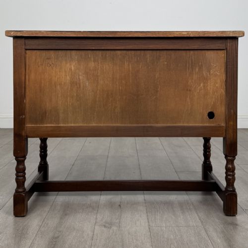 fig 6. A dark oak cupboard featuring two linenfold carved door panels, decorative metal hinges, ring pull handles, turned legs, and a lift top.