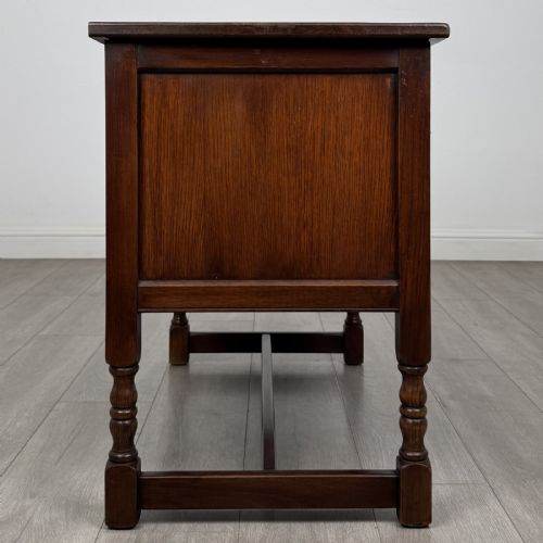 fig 8. A dark oak cupboard featuring two linenfold carved door panels, decorative metal hinges, ring pull handles, turned legs, and a lift top.