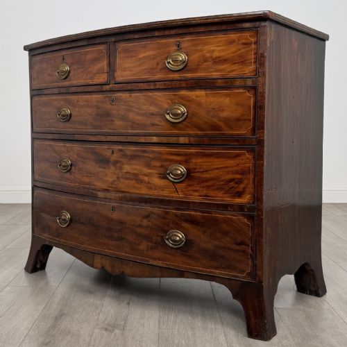 fig 1. An eighteenth-century Georgian bow-fronted mahogany chest of drawers with stringing inlay, oval brass handles, and splayed bracket feet.