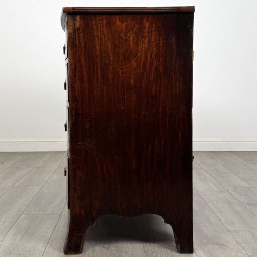 fig 2. An eighteenth-century Georgian bow-fronted mahogany chest of drawers with stringing inlay, oval brass handles, and splayed bracket feet.