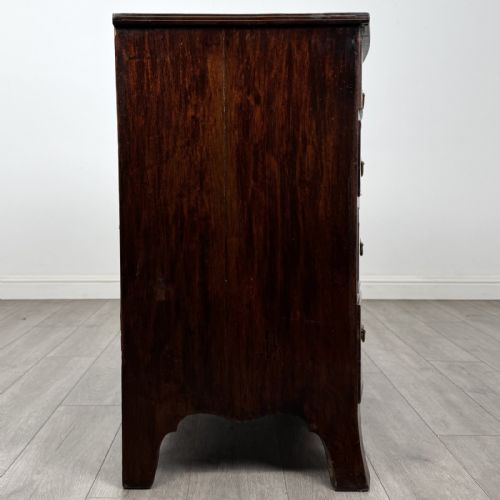 fig 6. An eighteenth-century Georgian bow-fronted mahogany chest of drawers with stringing inlay, oval brass handles, and splayed bracket feet.