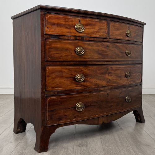 fig 7. An eighteenth-century Georgian bow-fronted mahogany chest of drawers with stringing inlay, oval brass handles, and splayed bracket feet.