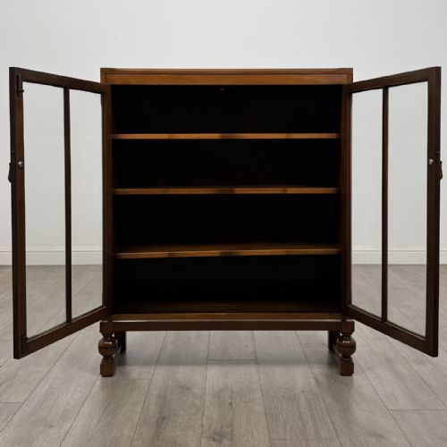 fig 1. A warm brown antique oak display cabinet featuring two glazed doors with wooden glazing bars and squat turned legs.