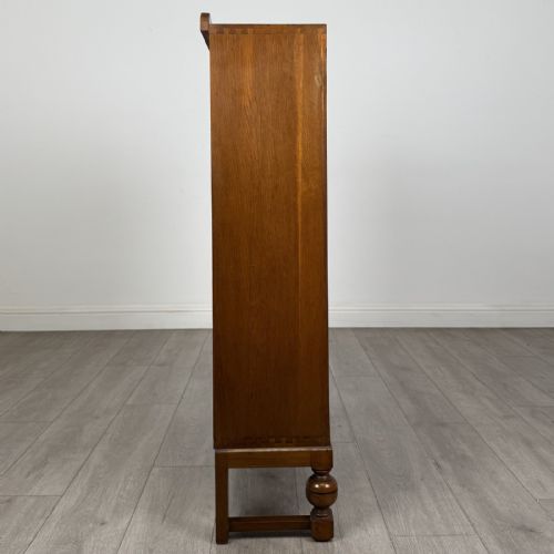 fig 7. A warm brown antique oak display cabinet featuring two glazed doors with wooden glazing bars and squat turned legs.