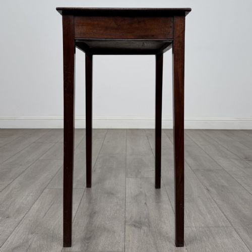 fig 6. An 18th-century Georgian mahogany side table with a single shallow drawer featuring a central circular brass pull, supported by four slim tapered legs.