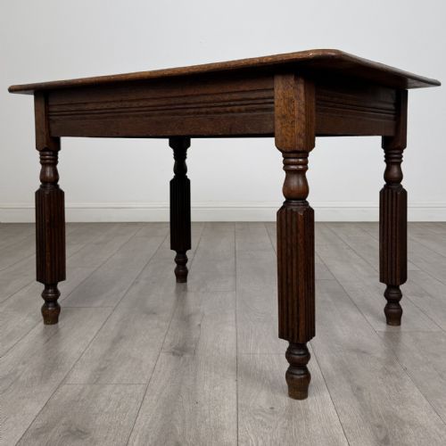 fig 1. An antique dark oak writing table featuring a rectangular top, moulded apron, and four turned reeded legs.
