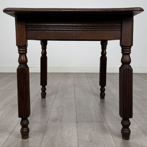 fig 2. An antique dark oak writing table featuring a rectangular top, moulded apron, and four turned reeded legs.