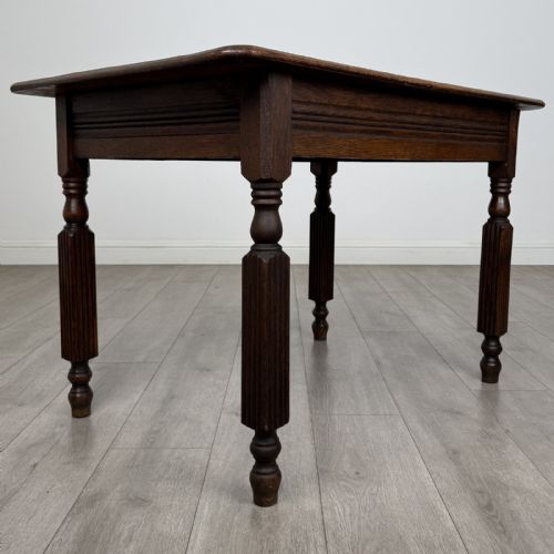 fig 3. An antique dark oak writing table featuring a rectangular top, moulded apron, and four turned reeded legs.