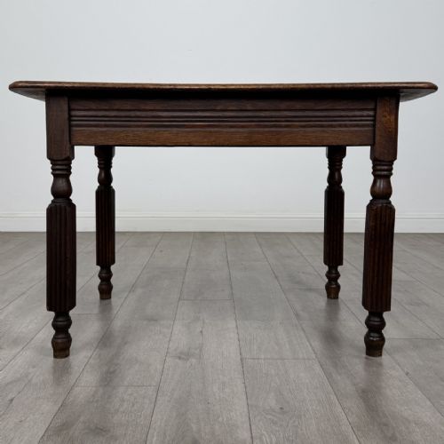 fig 4. An antique dark oak writing table featuring a rectangular top, moulded apron, and four turned reeded legs.