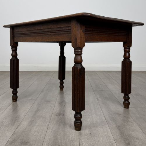 fig 5. An antique dark oak writing table featuring a rectangular top, moulded apron, and four turned reeded legs.
