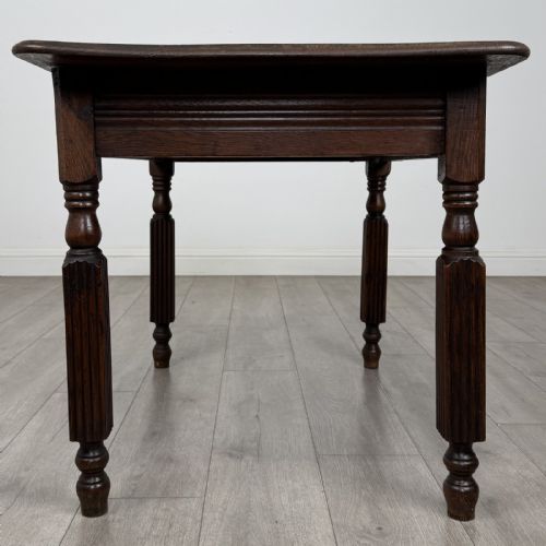 fig 6. An antique dark oak writing table featuring a rectangular top, moulded apron, and four turned reeded legs.