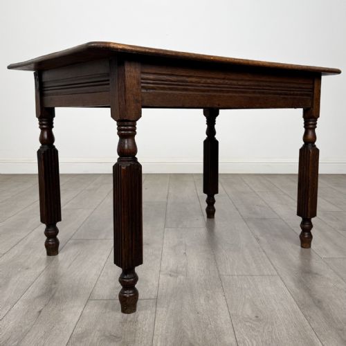 fig 7. An antique dark oak writing table featuring a rectangular top, moulded apron, and four turned reeded legs.