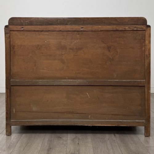 fig 5. A medium brown oak Art Deco sideboard featuring two drawers over two cabinet doors with long vertical carved wooden handles.