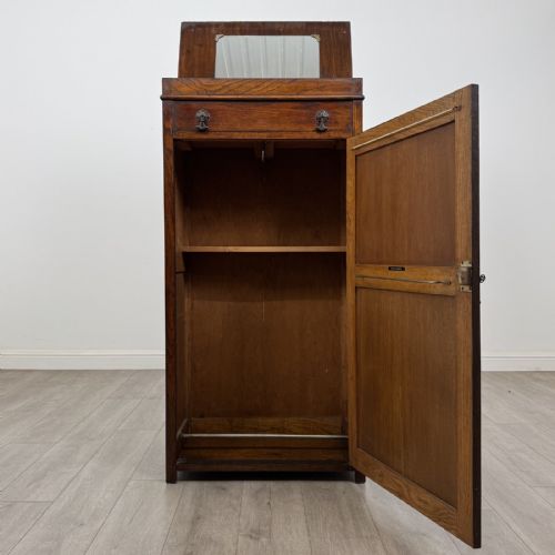 fig 1. A tall dark oak Edwardian storage cupboard featuring a lift-up top lid, panelled single door, and dark metal hardware.