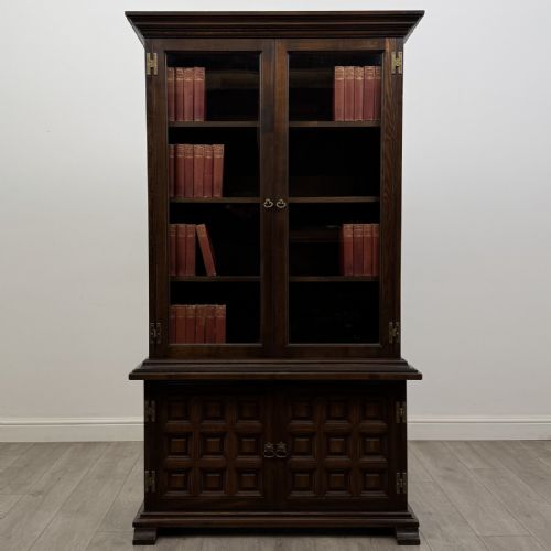 fig 1. A dark brown oak display cabinet featuring two glazed upper doors over two lower doors with carved geometric panels.