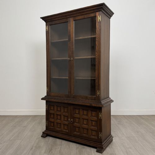 fig 3. A dark brown oak display cabinet featuring two glazed upper doors over two lower doors with carved geometric panels.
