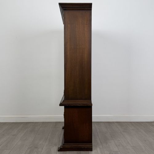 fig 4. A dark brown oak display cabinet featuring two glazed upper doors over two lower doors with carved geometric panels.