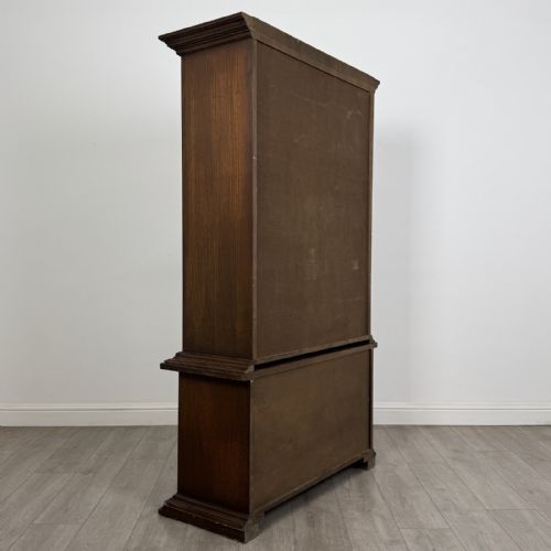 fig 5. A dark brown oak display cabinet featuring two glazed upper doors over two lower doors with carved geometric panels.