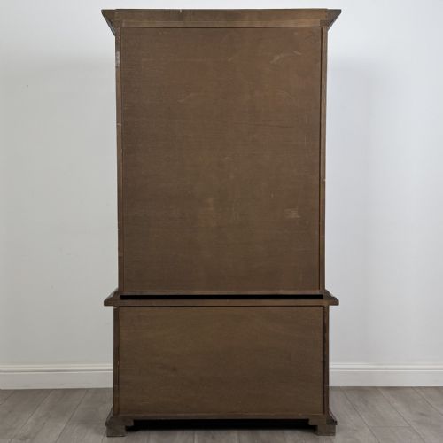 fig 6. A dark brown oak display cabinet featuring two glazed upper doors over two lower doors with carved geometric panels.