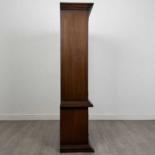 fig 8. A dark brown oak display cabinet featuring two glazed upper doors over two lower doors with carved geometric panels.
