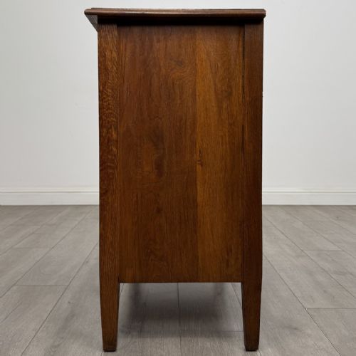 fig 2. An Edwardian golden oak chest of drawers featuring three full-width drawers with aged brass drop handles, supported by square tapered legs.