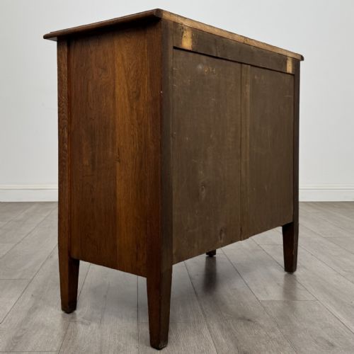 fig 3. An Edwardian golden oak chest of drawers featuring three full-width drawers with aged brass drop handles, supported by square tapered legs.
