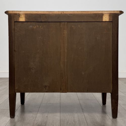 fig 4. An Edwardian golden oak chest of drawers featuring three full-width drawers with aged brass drop handles, supported by square tapered legs.