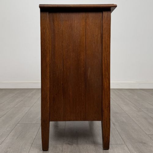 fig 5. An Edwardian golden oak chest of drawers featuring three full-width drawers with aged brass drop handles, supported by square tapered legs.