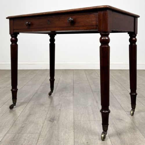 fig 1. Victorian mahogany writing table featuring a single frieze drawer with turned wooden knobs and four turned legs on brass castors.