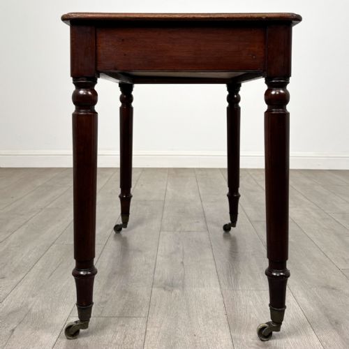 fig 2. Victorian mahogany writing table featuring a single frieze drawer with turned wooden knobs and four turned legs on brass castors.