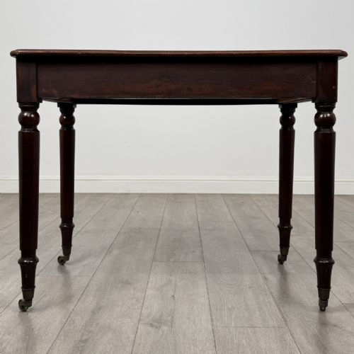 fig 4. Victorian mahogany writing table featuring a single frieze drawer with turned wooden knobs and four turned legs on brass castors.