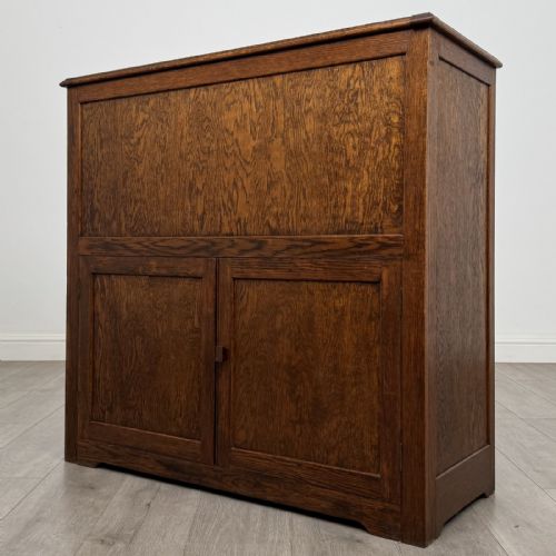 fig 2. An antique dark oak fitted cupboard featuring a smooth top section above two panelled lower cupboard doors.