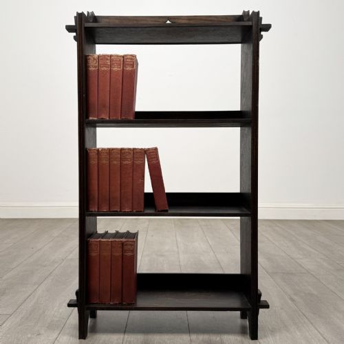 fig 1. A compact dark oak open bookcase featuring four tiered shelves, side uprights with exposed tenon projections, and a low top gallery rail.