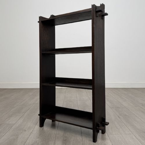 fig 2. A compact dark oak open bookcase featuring four tiered shelves, side uprights with exposed tenon projections, and a low top gallery rail.