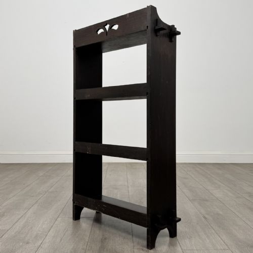 fig 6. A compact dark oak open bookcase featuring four tiered shelves, side uprights with exposed tenon projections, and a low top gallery rail.