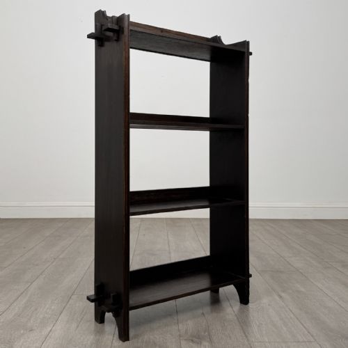 fig 8. A compact dark oak open bookcase featuring four tiered shelves, side uprights with exposed tenon projections, and a low top gallery rail.