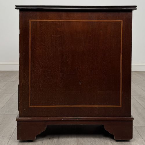 fig 2. A Victorian mahogany pedestal desk featuring a breakfront design, nine drawers with inlaid border details, brass swan-neck handles, and bracket feet.