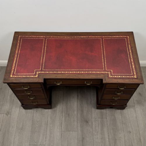 fig 8. A Victorian mahogany pedestal desk featuring a breakfront design, nine drawers with inlaid border details, brass swan-neck handles, and bracket feet.