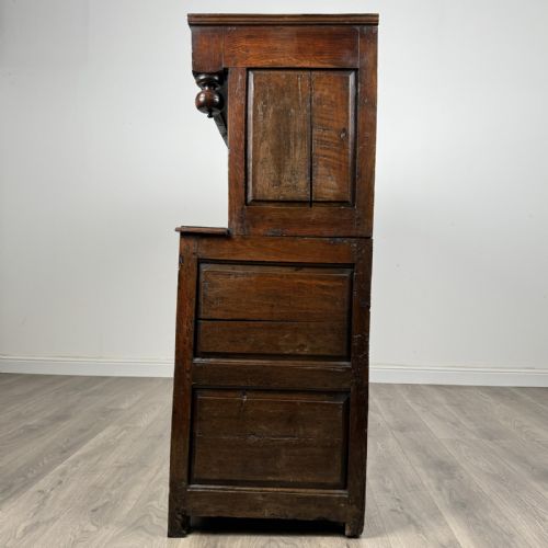 fig 3. An 18th-century Georgian dark oak Welsh deuddarn cupboard featuring carved upper panels dated 1743, turned drop pendants, and panelled cupboard doors.