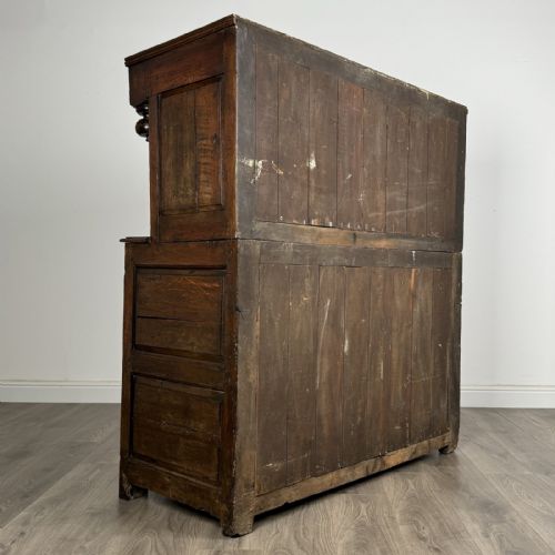 fig 4. An 18th-century Georgian dark oak Welsh deuddarn cupboard featuring carved upper panels dated 1743, turned drop pendants, and panelled cupboard doors.