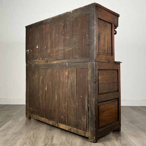 fig 6. An 18th-century Georgian dark oak Welsh deuddarn cupboard featuring carved upper panels dated 1743, turned drop pendants, and panelled cupboard doors.