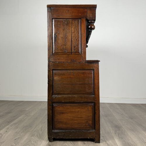fig 7. An 18th-century Georgian dark oak Welsh deuddarn cupboard featuring carved upper panels dated 1743, turned drop pendants, and panelled cupboard doors.