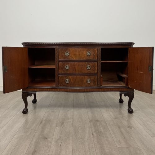 fig 1. An Edwardian mahogany sideboard with three central drawers flanked by cupboard doors featuring oval mahogany veneers and carved cabriole legs terminating in ball-and-claw feet.